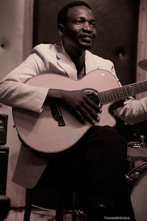 Juma Tutu seated with a guitar in a studio setting