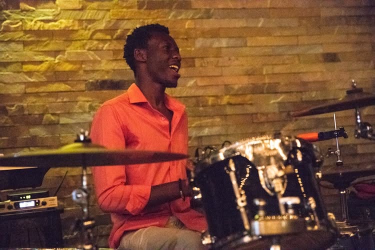 Drummer smiling behind a drum kit