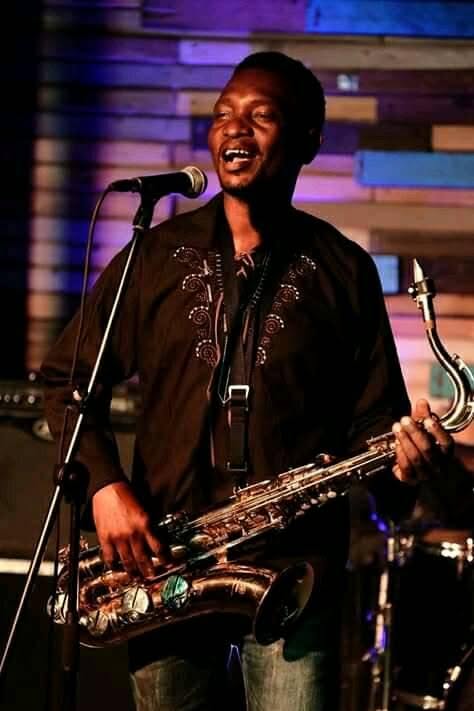 Juma Tutu singing while holding a saxophone